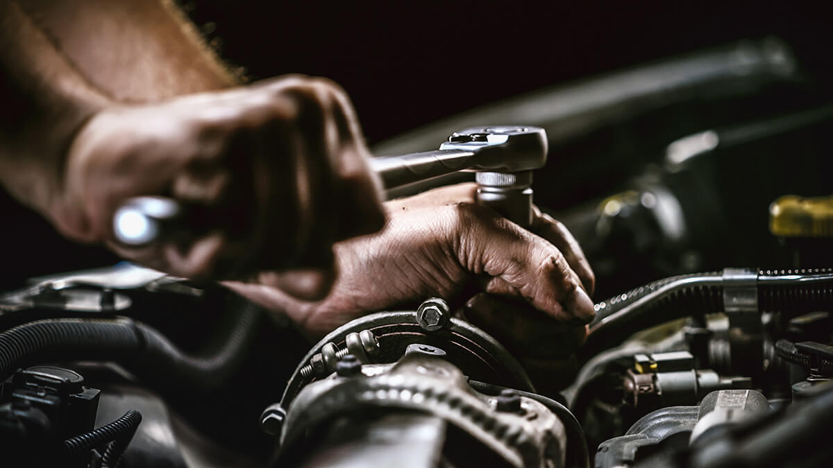 Auto mechanic working on car engine