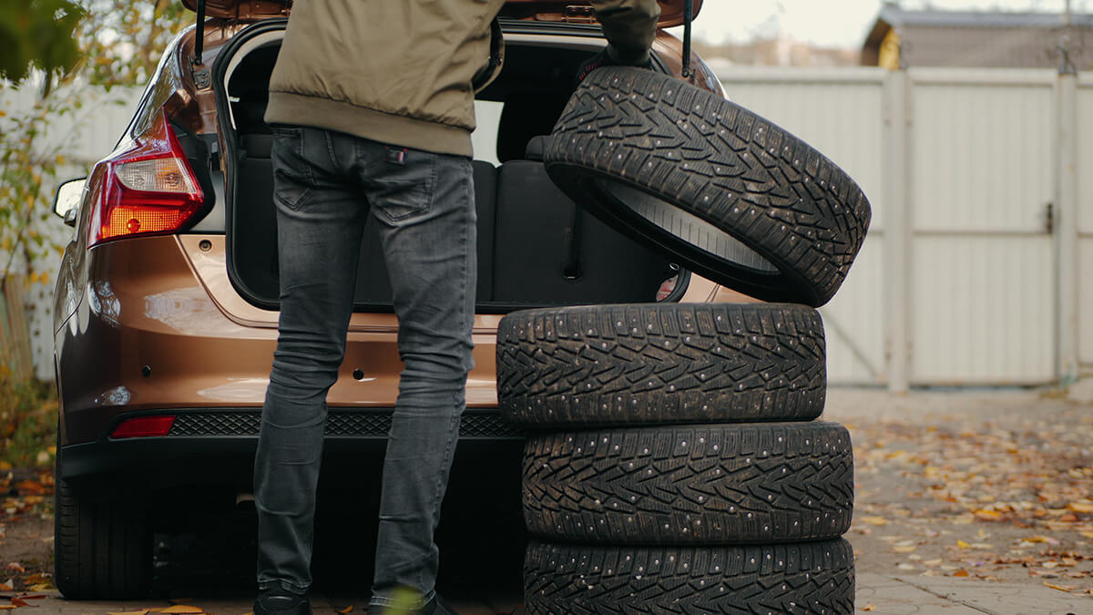 A man puts winter tires in the trunk of a car